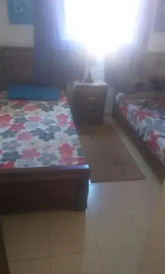 a room with two beds and a table and a bed sidx sidx sidx at Vue Neige et Forêt Ifrane bien au chaud 3 pieces in Ifrane