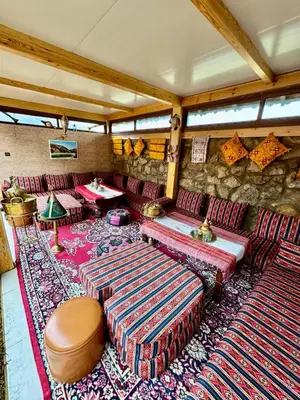 a living room with couches and a stone wall at Auberge Sous Les Étoiles Lac Ouiouane in Kasba des Aït Athmane