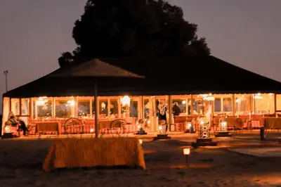 a building with an umbrella and tables and chairs at night at Incredible luxury Camp in Merzouga