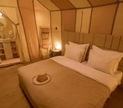 a bed with a hat sitting on top of it at Merzouga Marvelous Camp in Merzouga