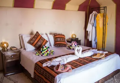 a bedroom with a bed with towels and swans on it at Merzouga Glossy Camp in Merzouga