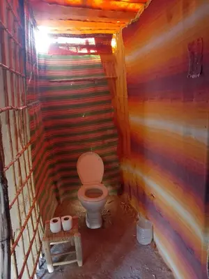 a bathroom with a toilet in a wooden wall at Merzouga your Tour Nigths in Camp in Merzouga