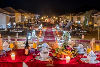 a table with plates of fruit and candles on it at Diamond luxury camp in Merzouga