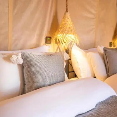 a bedroom with two beds with pillows and a lamp at Merzouga Spectacular Luxury Camp in Merzouga
