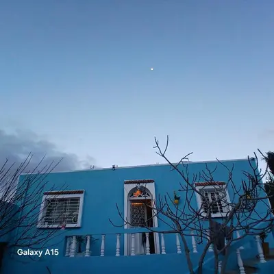 a blue building with a door and two windows at Maison d'Azur in Sidi Abdalwahad