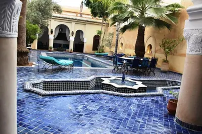 a courtyard with a pool with tables and chairs at Chambres Émeraude et Rubis - Riad Lotus Bleu in Fès