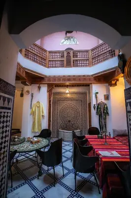 a room with two tables and chairs and a wall at Dar Nana fes in Fès