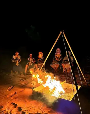 a group of people sitting around a fire at Merzougadreamcamp in Merzouga