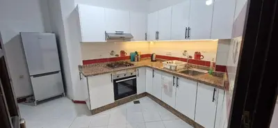 a small kitchen with white cabinets and a refrigerator at Appartement de charme in Fès