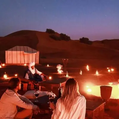 a group of people sitting around a table in the desert at Merzouga Berber Luxury Camp in Merzouga