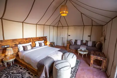 a bedroom in a tent with a bed and a couch at Morocco Tours Camp in Merzouga