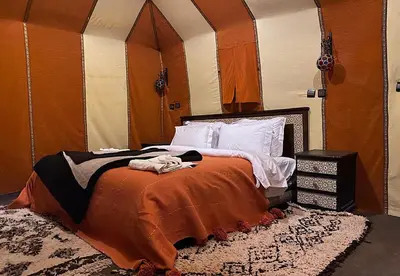 a bedroom with a bed with an orange blanket at Desert Camp in Merzouga