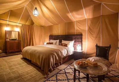 a bedroom with a bed and a table in a tent at Desert Camp in Merzouga