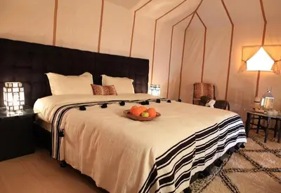 a bedroom with a bed with a bowl of fruit on it at Amidinine Desert Camp in Merzouga