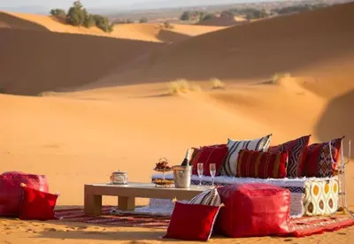 a table with red and blue pillows in the desert at Amodo desert camp in Merzouga