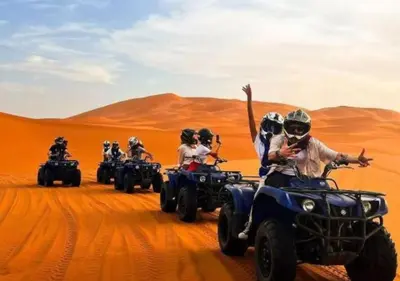 a group of people riding on atvs in the desert at Moroccan luxury camp in Merzouga