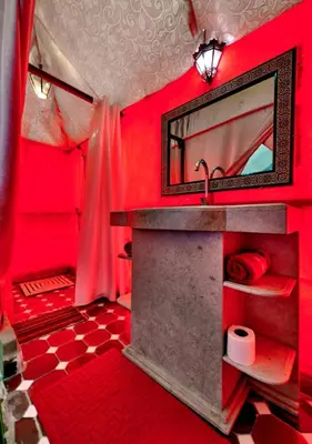 a red bathroom with a sink and a mirror at Desert Berber Luxury Camp in Merzouga