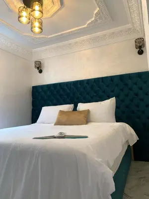 a bedroom with a large bed with a blue headboard at RIAD Jad in Fès