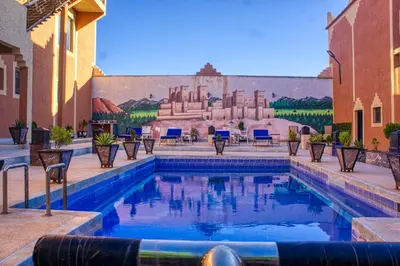 a swimming pool with chairs and a mural on a building at Lamtounipalace in Ouarzazate