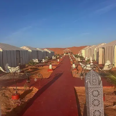 a road leading to a row of houses in the desert at Nada luxury desert camp in Merzouga