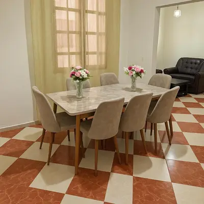 a dining room table with chairs and vases with flowers on it at Residence Kawtar Meknès Marjane 2 in Meknès