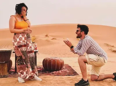 a man and a woman sitting in the desert at Fantastic Luxury Camp in Merzouga