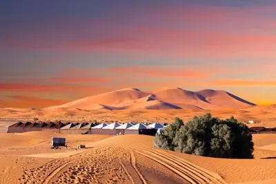 a desert with a building in the middle of it at Desert camp nights camel ride in Merzouga
