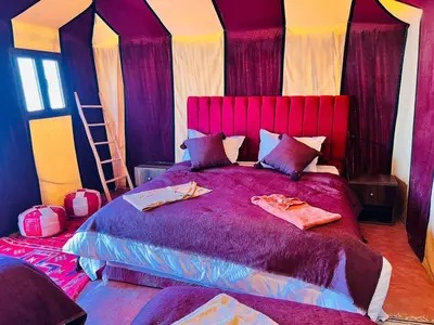 a bedroom with a large purple bed with pillows at Merzouga in Oulad Akkou