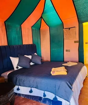 a bedroom with a bed in a room with colorful walls at Merzouga in Oulad Akkou