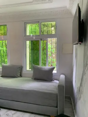 a bed sitting in a room with two windows at Appartement bel kayed in Fès