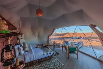 a bedroom with a bed and a large window at Unique Desert Camp in Merzouga