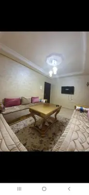 a living room with a table and a couch at Appartement à côté la plage in Oulad Akkou