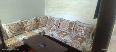 a couch with pillows on it with a table at apartment raha in Oulad Akkou
