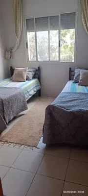 a bedroom with two beds and two windows at Appartement meublée in Oulad Akkou