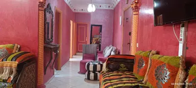 a living room with pink walls and colorful furniture at Appartement meublée in Oulad Akkou
