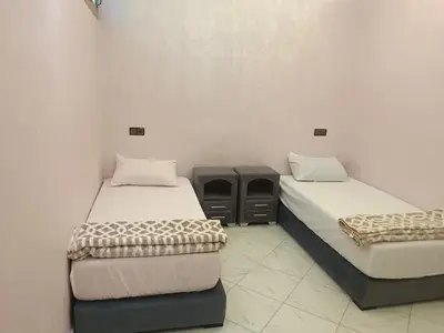 a room with two beds and a table in it at Hay nahda dakhla in Oulad Akkou