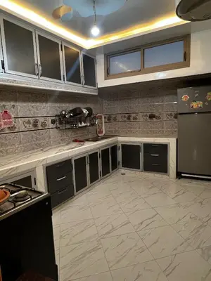 a kitchen with gray cabinets and a black refrigerator at Hay nahda dakhla in Oulad Akkou