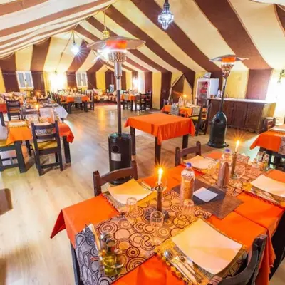a dining room with orange tables and chairs at Desert Bloom Luxury Camp in Merzouga
