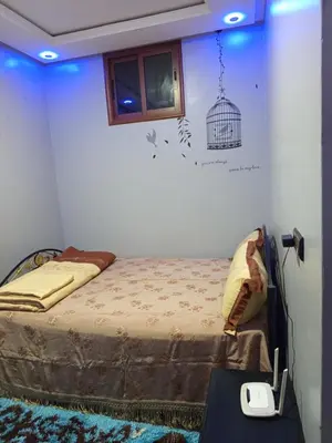 a bedroom with a bed and a bird cage on the wall at El farah in Oulad Akkou