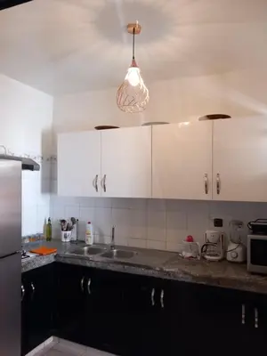 a kitchen with white cabinets and a sink and a light at Al boustane1 in Oulad Akkou