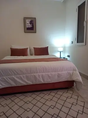 a large bed in a bedroom with a white wall at Al boustane1 in Oulad Akkou