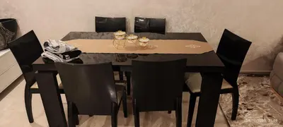 a dining room table with black chairs and a black table with ahibition at Appartement agadir bay bien ensoleillé in Oulad Akkou