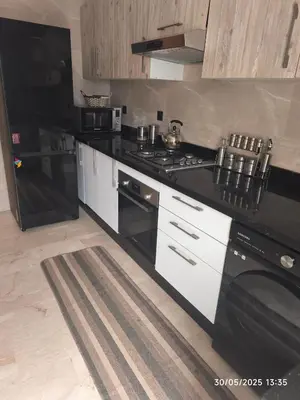 a kitchen with a black stove and a refrigerator at Appartement agadir bay bien ensoleillé in Oulad Akkou