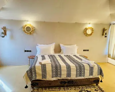 a bedroom with a large bed with two mirrors on the wall at Luxurious magic camp in Merzouga