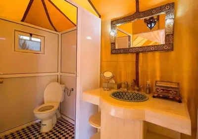 a bathroom with a toilet and a sink and a mirror at Sahara Luxurious Tented in Merzouga