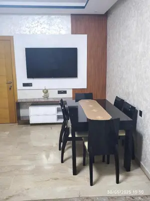a dining room with a table and chairs and a television at Appartement luxe in Oulad Akkou