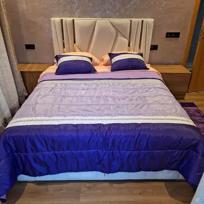 a large bed with purple comforter and blue pillows at Appartement luxe in Oulad Akkou