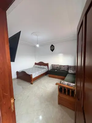 a living room with a couch and a bed at Apartment for rent by the day in Oulad Akkou