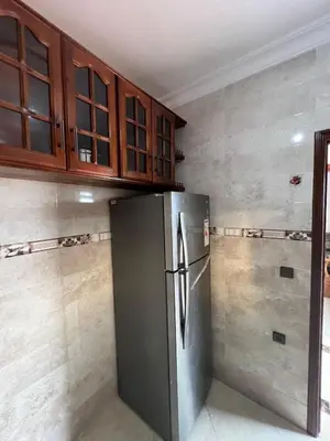 a kitchen with a stainless steel refrigerator and wooden cabinets at Apartment for rent by the day in Oulad Akkou