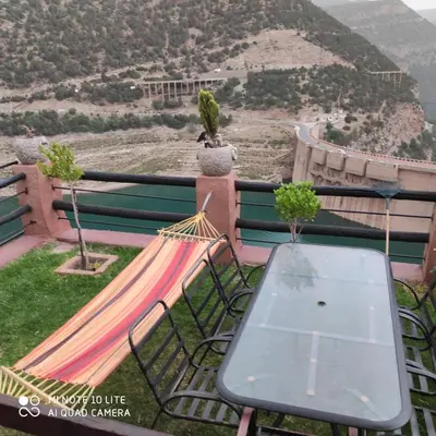 a hammock with a table and a view of a mountain at Villa de rêve in Bine el Ouidane
